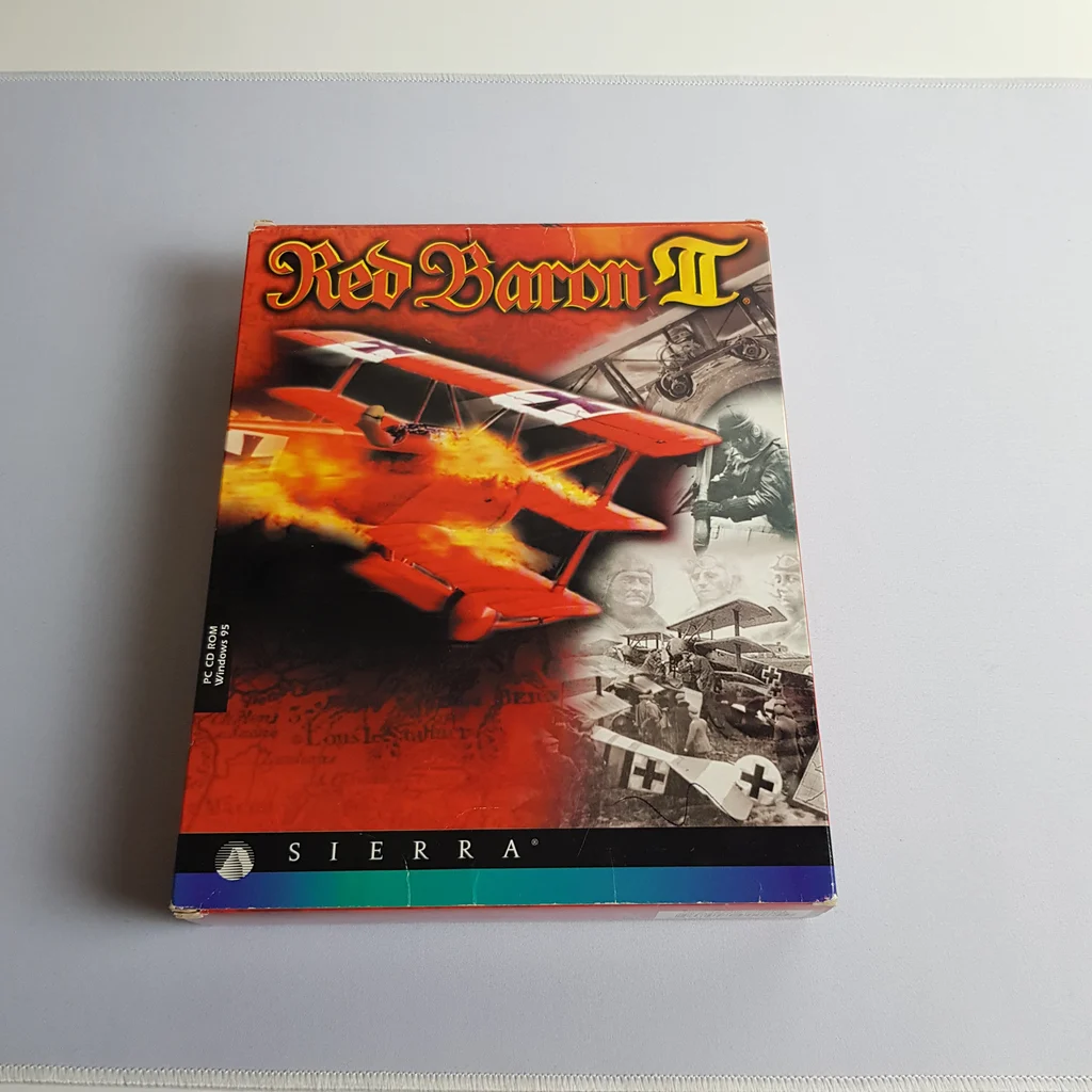 Red Baron II PC játék dobozának előlapi képe, piros repülőgéppel és történelmi jelenetekkel.