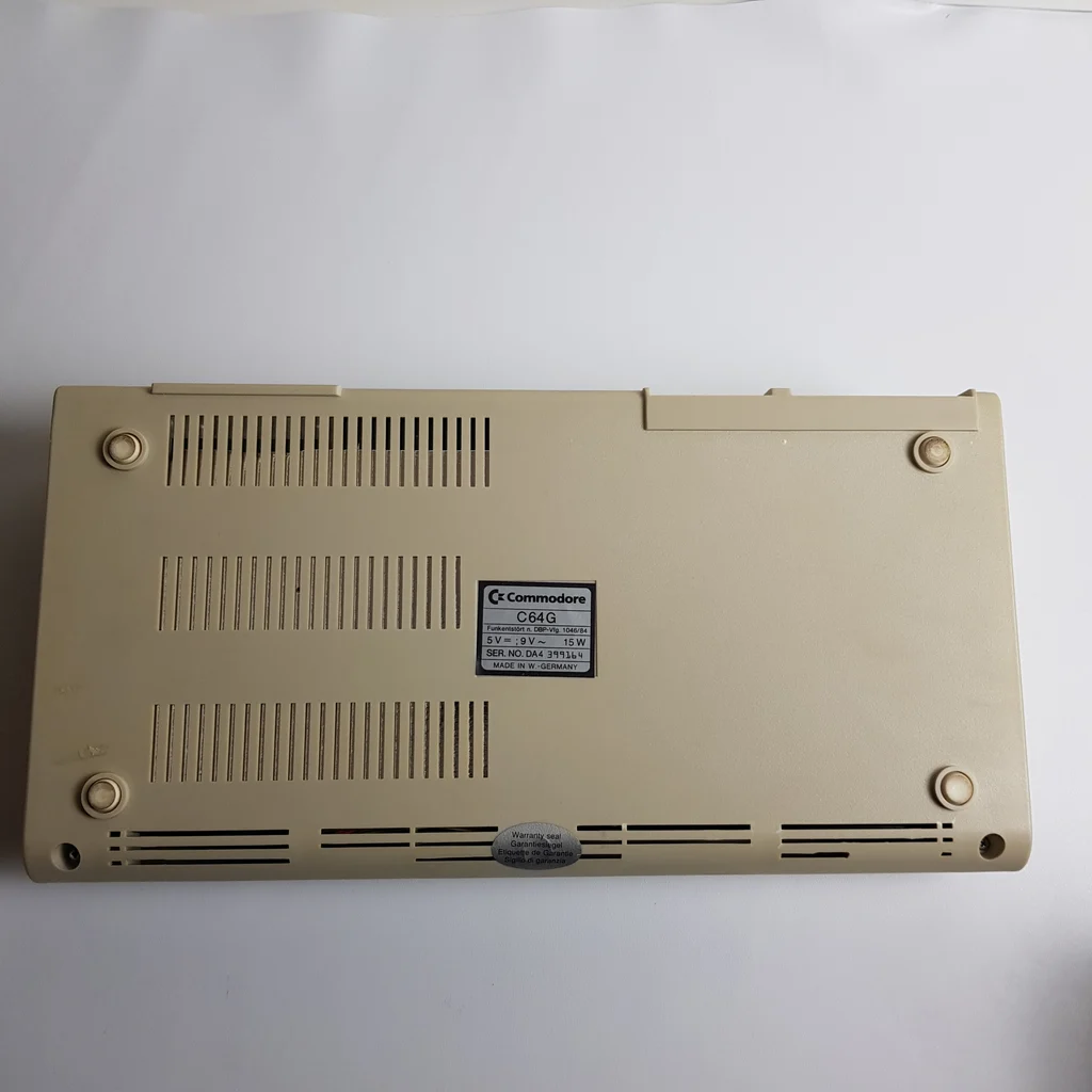 Commodore C64G számítógép alulnézetből, látható címkével