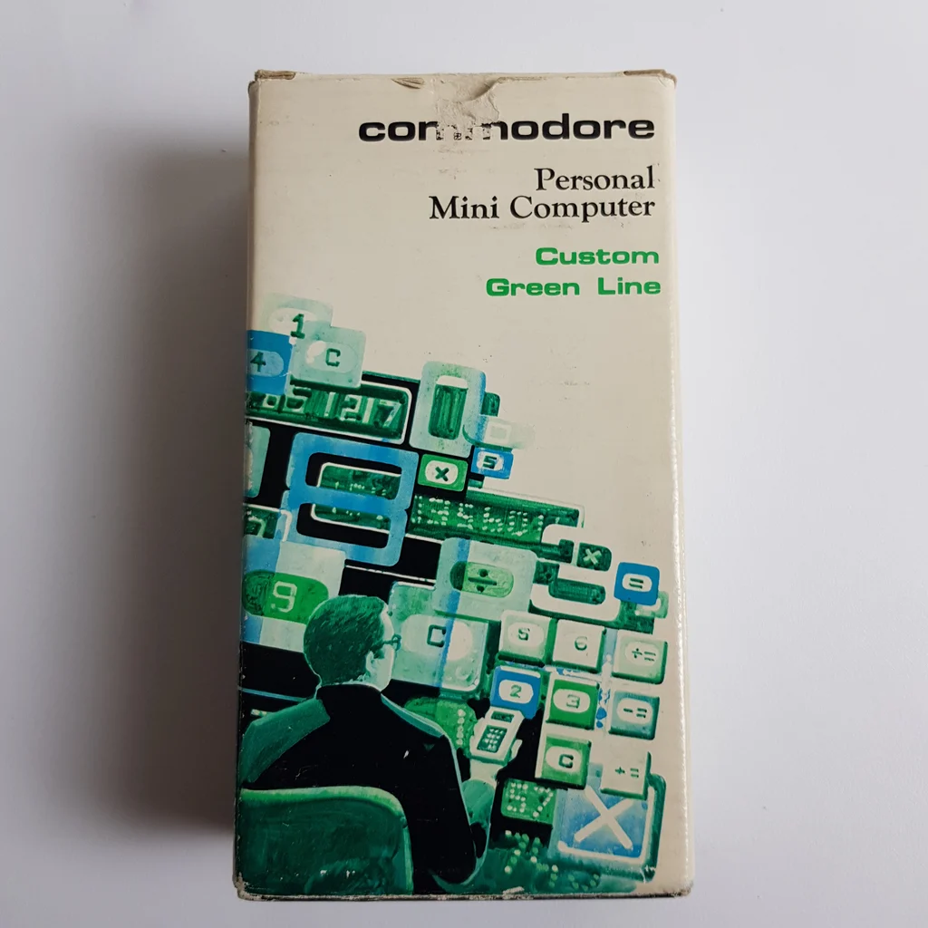 Commodore SR-1800 számológép doboza fehér háttéren, zöld és kék grafikával.