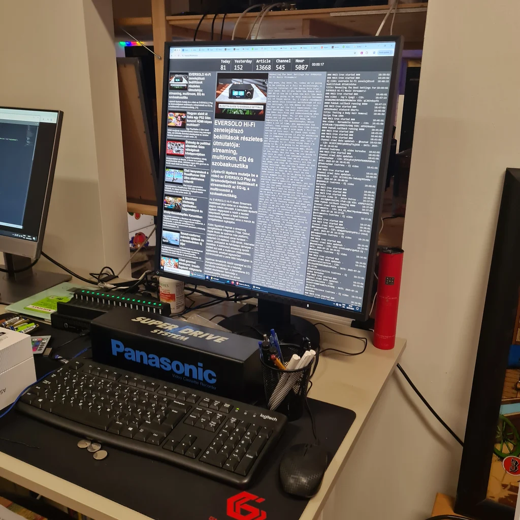 Számítógépes munkaállomás nagy monitorral, Panasonic feliratú eszközzel, billentyűzettel és egérrel.