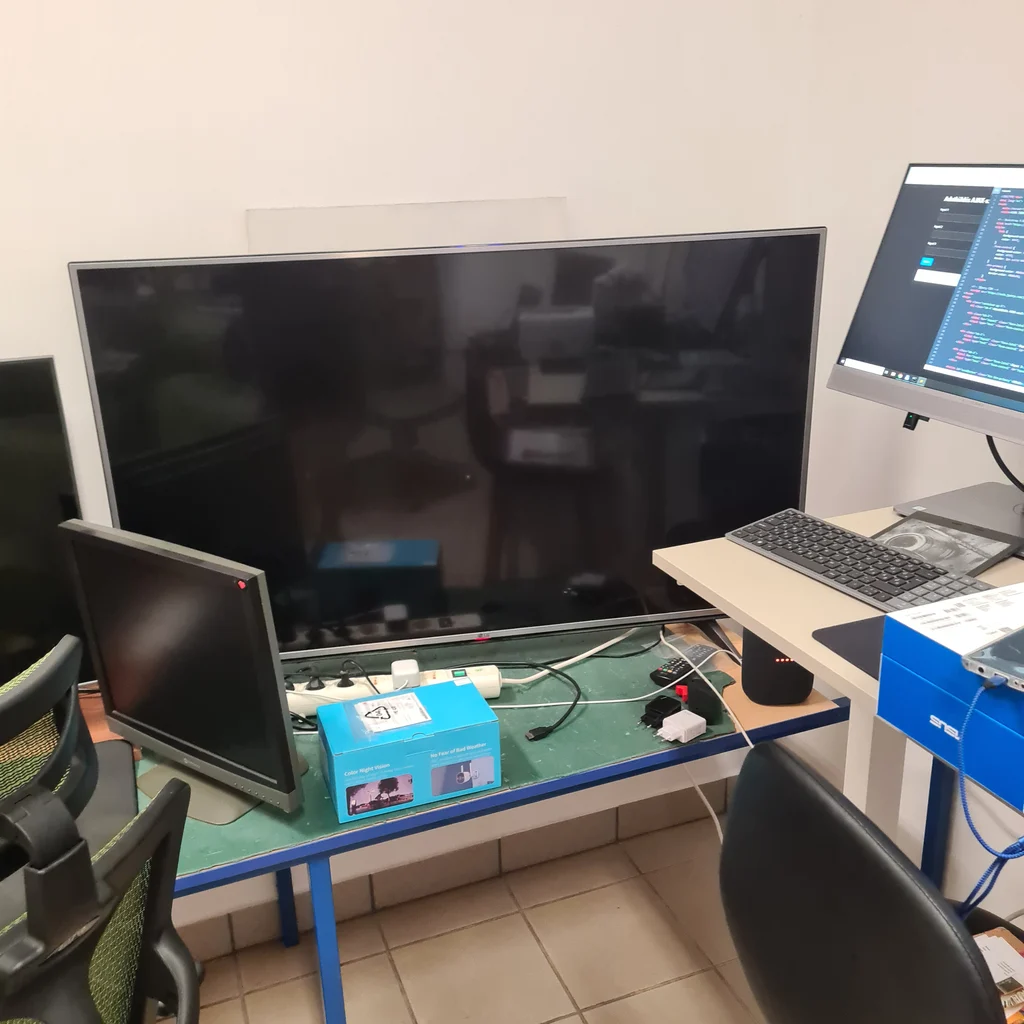 Három különböző méretű monitor egy asztalon, irodai környezetben.