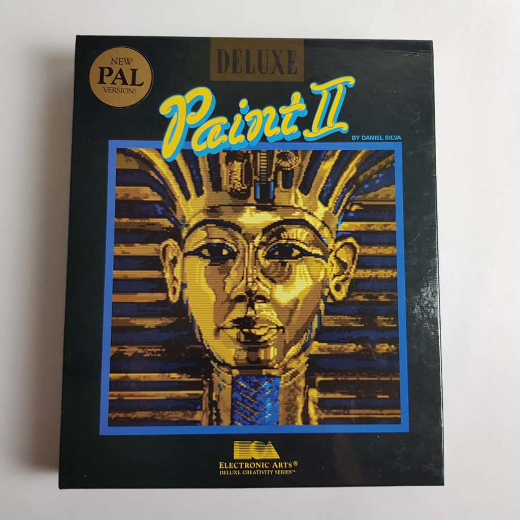 Deluxe Paint II Amiga szoftver doboz elölről A Deluxe Paint II Amiga szoftver díszdoboza, arany maszk grafikával az elején.