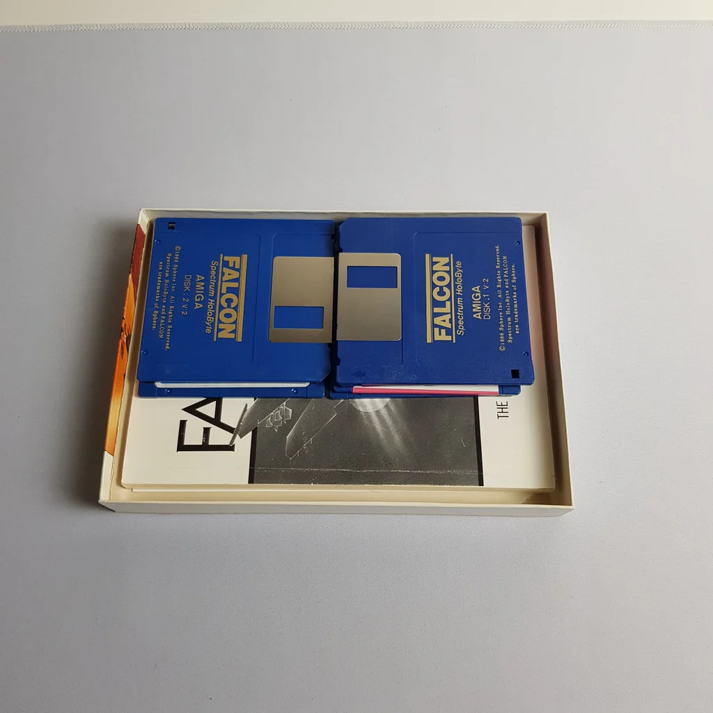 Falcon Amiga videojáték tartalma lemezekkel és kézikönyvvel A Falcon Amiga videojáték dobozának tartalma, benne két floppy lemez és kézikönyv.