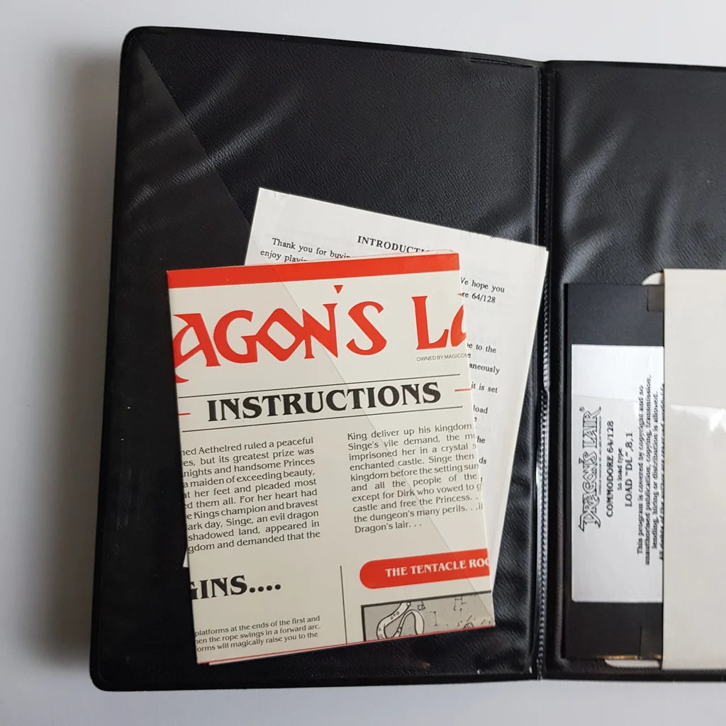 Dragon's Lair kézikönyv és dokumentáció Dragon's Lair kézikönyv és egyéb papírok egy fekete tokban